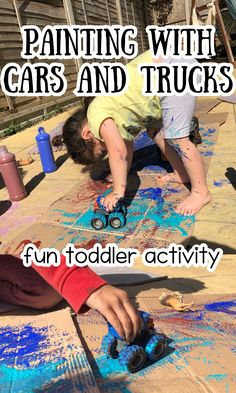 two children are playing with cars and trucks on the ground, while one child is using scissors