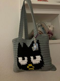 a crocheted tote bag with an angry cat face on the front and bottom