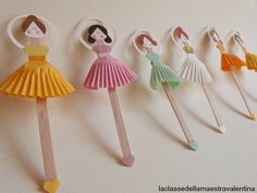 several paper dolls are hanging on the wall with toothpicks in each one's hands