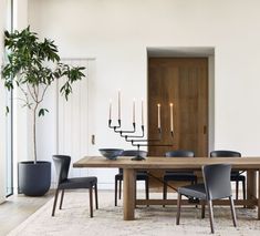 a dining room table with chairs and candles on it in front of a door that leads to another room