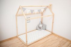 a dollhouse bed made out of wood and white fabric with a pillow on the bottom