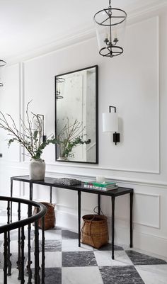 a black and white checkered floor in a room with a table, mirror and vase