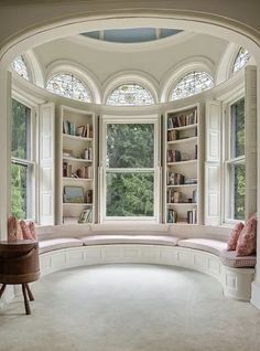 an arched window in the corner of a room with bookshelves on either side