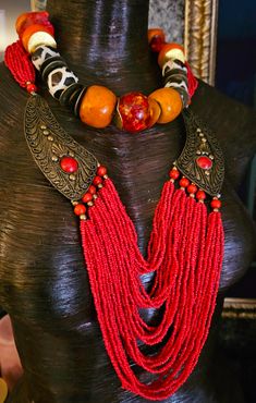 Here's a Bohemian Necklace and Bib Set I found in my inventory. The longer strand is a vintage piece that I did not make. It measures a non-adjustable 28" and closes with a button and a loop. Multiple strands of red-orange seed beads comprise the majority of the piece and two ornate metal accents (looks like bronze) are symmetrically set on each side with an orange-red cabochon (jade??). The shorter necklace is one that I made. It measures a non-adjustable 19" and features the following components: Tibetan resin, Moroccan resin, Zebu bone*, gold tone metal spacers, vintage Chinese brass coins, red branch corals, vintage brass beads and round tiger's eye. Closes with a gold tone hook and eye. Pair them together, or wear separately. These also will mix and match well with your personal favor Vintage Red Hand-strung Beaded Necklaces, Unique Hand-strung Multi-strand Necklace, Adjustable Large Beads Jewelry For Rituals, Bohemian Hand-strung Jewelry For Rituals, Handmade Vintage Beaded Necklaces For Festivals, Vintage Adjustable Necklaces With Colorful Beads, Handmade Vintage Beads For Festival, Handmade Vintage Beaded Necklace For Festivals, Vintage Adjustable Beaded Necklaces For Festivals