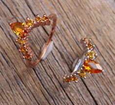 two rings with different colored stones on top of a wooden table next to each other