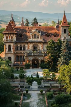 an old mansion with many windows and towers in the middle of a garden area surrounded by trees