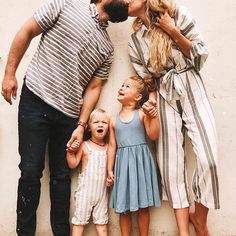 a man and two women kissing while three children stand next to each other in front of a white wall