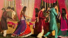 a group of people standing around each other in front of a stage with pink drapes