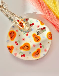 a white plate with fruit designs on it next to a yellow and red feather holder