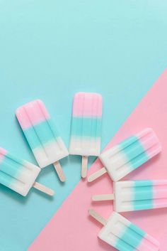 five popsicles with blue and pink stripes on a pastel colored background, top view