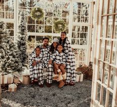 a group of people sitting next to each other in front of a christmas tree with presents