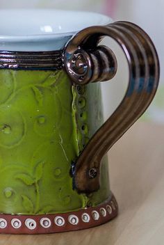 a green and white mug sitting on top of a wooden table