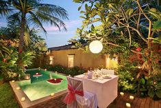 an outdoor dining area next to a pool with candles on the table and chairs around it