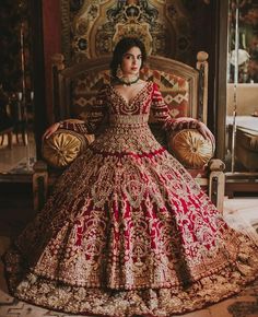 a woman in a red and gold wedding dress sitting on a chair talking on the phone