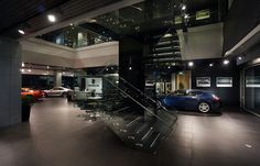 a car is parked in the garage next to a stair case with glass railings