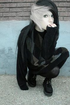 a woman sitting on the ground with her hands in her mouth and wearing black shoes