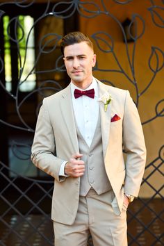 a man in a suit and bow tie posing for a photo with his hands in his pockets