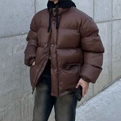 a man standing on the sidewalk wearing a brown puffy jacket and black beanie