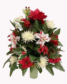 a vase filled with red and white flowers on top of a green planter covered in greenery