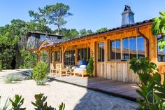 a small wooden house sitting on top of a sandy beach next to trees and bushes