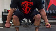 a man squats down while holding a barbell in front of his face and chest