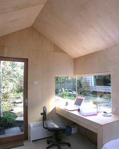 a laptop computer sitting on top of a wooden desk next to a glass door in a room