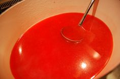 a spoon in a bowl filled with red liquid