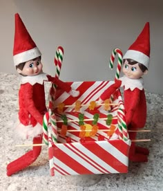 two elfs with candy canes and candies in a box on the table