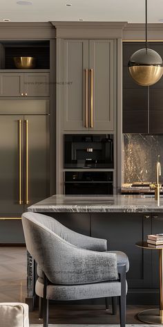 a modern kitchen with an island and gold accents on the cabinets, along with a gray chair