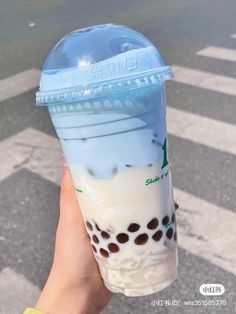 someone holding up a plastic cup filled with milkshake and ice cream on the street