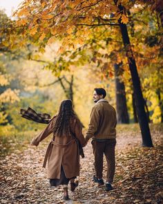 a man and woman walking down a leaf covered path