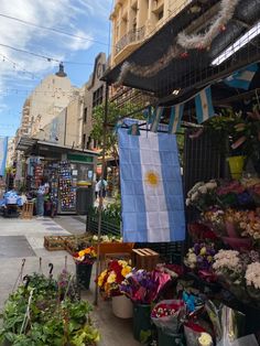 an outdoor market with flowers and plants on the sidewalk