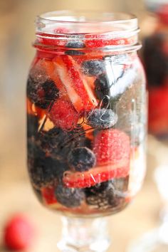 a jar filled with berries and strawberries on top of a table