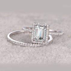 an emerald cut diamond ring with pave diamonds on the band