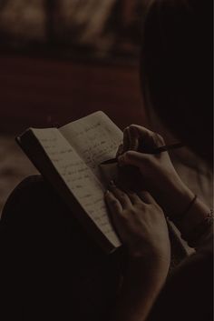 a person writing on a notepad with a pen in their hand and holding a notebook