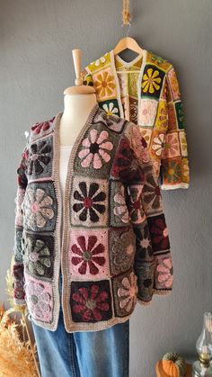 a crocheted jacket is hanging on a mannequin's head and it has flowers in the center