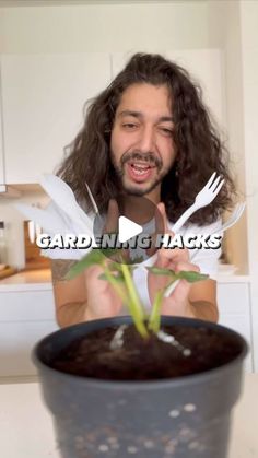 a man with long hair holding a knife and fork over a potted plant