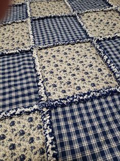 a blue and white patchwork quilt is laying on top of a tablecloth that has been made into a blanket