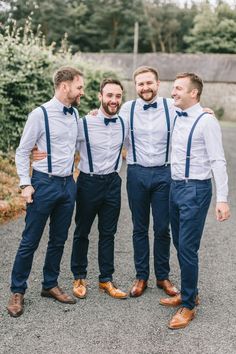 three men in blue pants and bow ties posing for the camera with their arms around each other