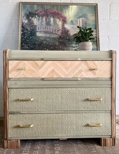 an old dresser is painted green and gold with chevron patterns on the drawers, along with a potted plant