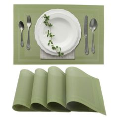 a place setting with napkins, silverware and a green place mat on the table