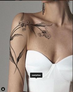 a woman wearing a white strapless dress with flowers on her arm and shoulder tattoo