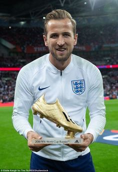 the soccer player is holding his golden shoe in front of him and smiling at the camera