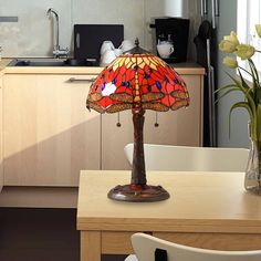 a table lamp sitting on top of a wooden table next to a vase filled with flowers