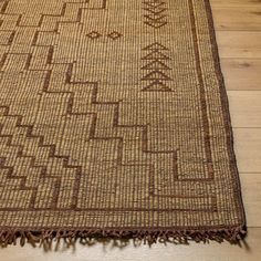 a brown and tan area rug on the floor with wooden planks in the background