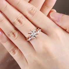 a woman's hand holding a ring with two stars on the middle of it