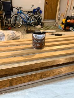 a can of wood sitting on top of a wooden bench in a room with bikes