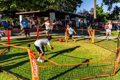 children playing soccer on the grass in an open area with orange net and red posts