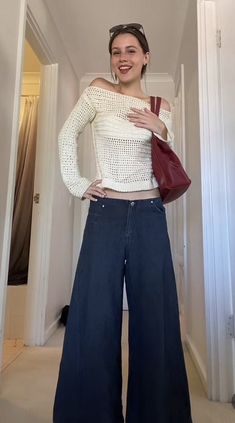 a woman standing in a hallway with her hands on her hips and wearing wide legged jeans