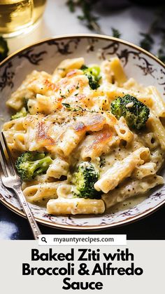 baked ziti with broccoli and alfredo sauce in a bowl next to a glass of wine